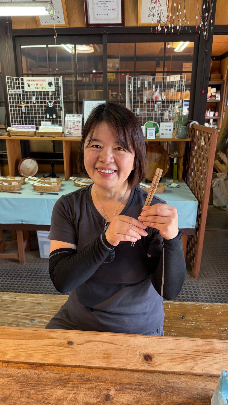 Shoko, Kumamoto guide and washi notebook workshop instructor, smiling and holding a pair of chopsticks