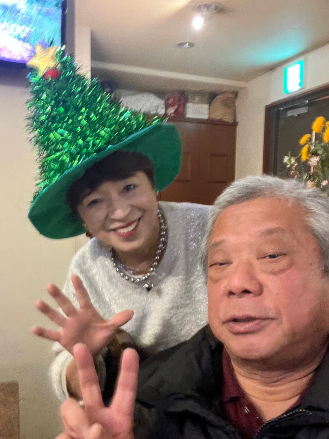 Two people smiling at the bar, one wearing a festive green hat