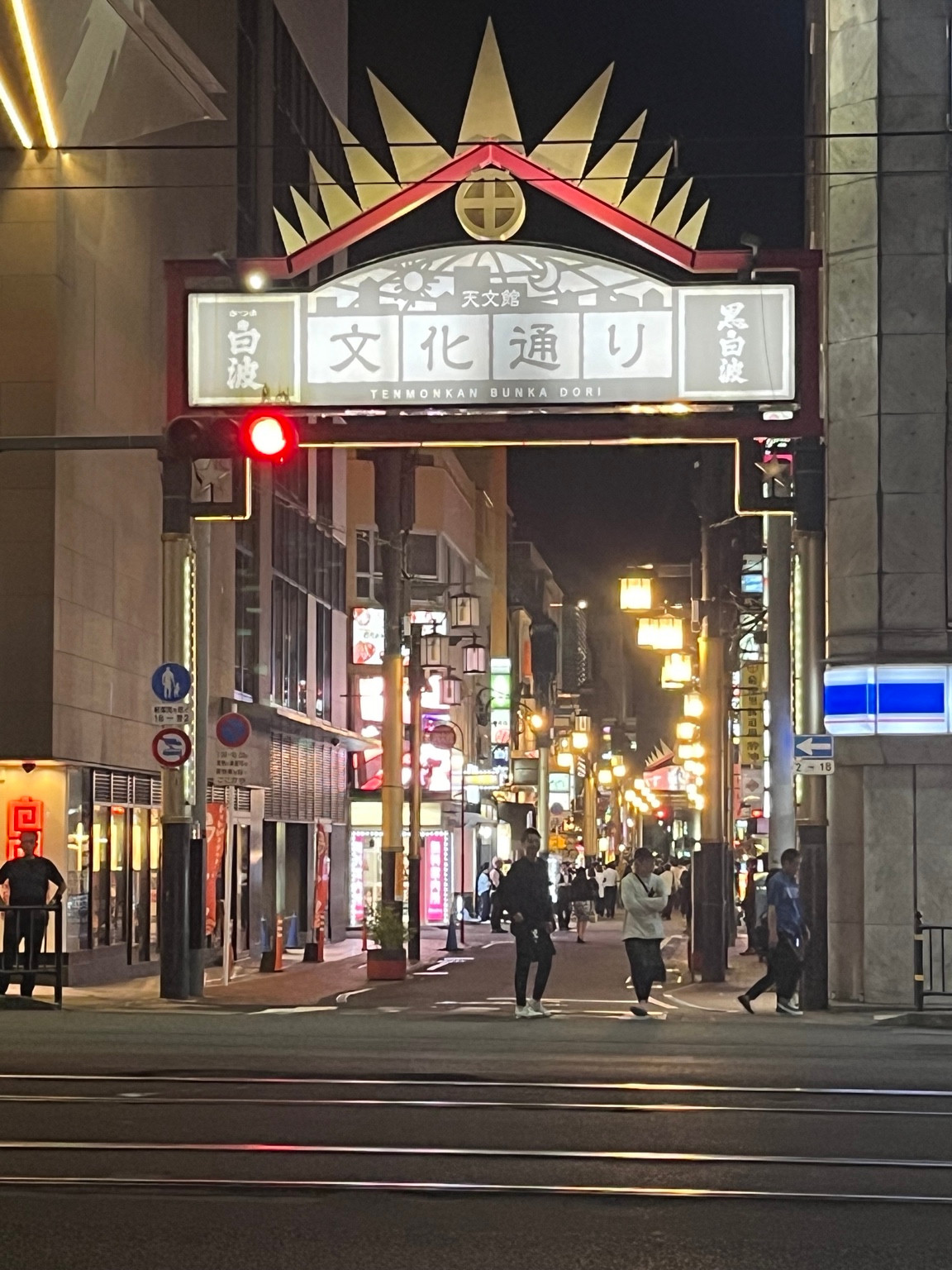 The illuminated Tenmonkan Bunka Dori gate above a street at night