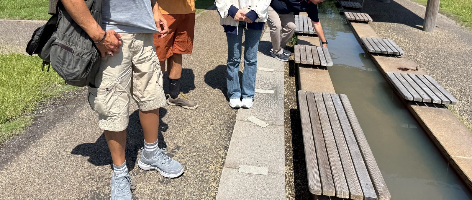 A student volunteer walking with guests at a hot spring foot bath in Kagoshima