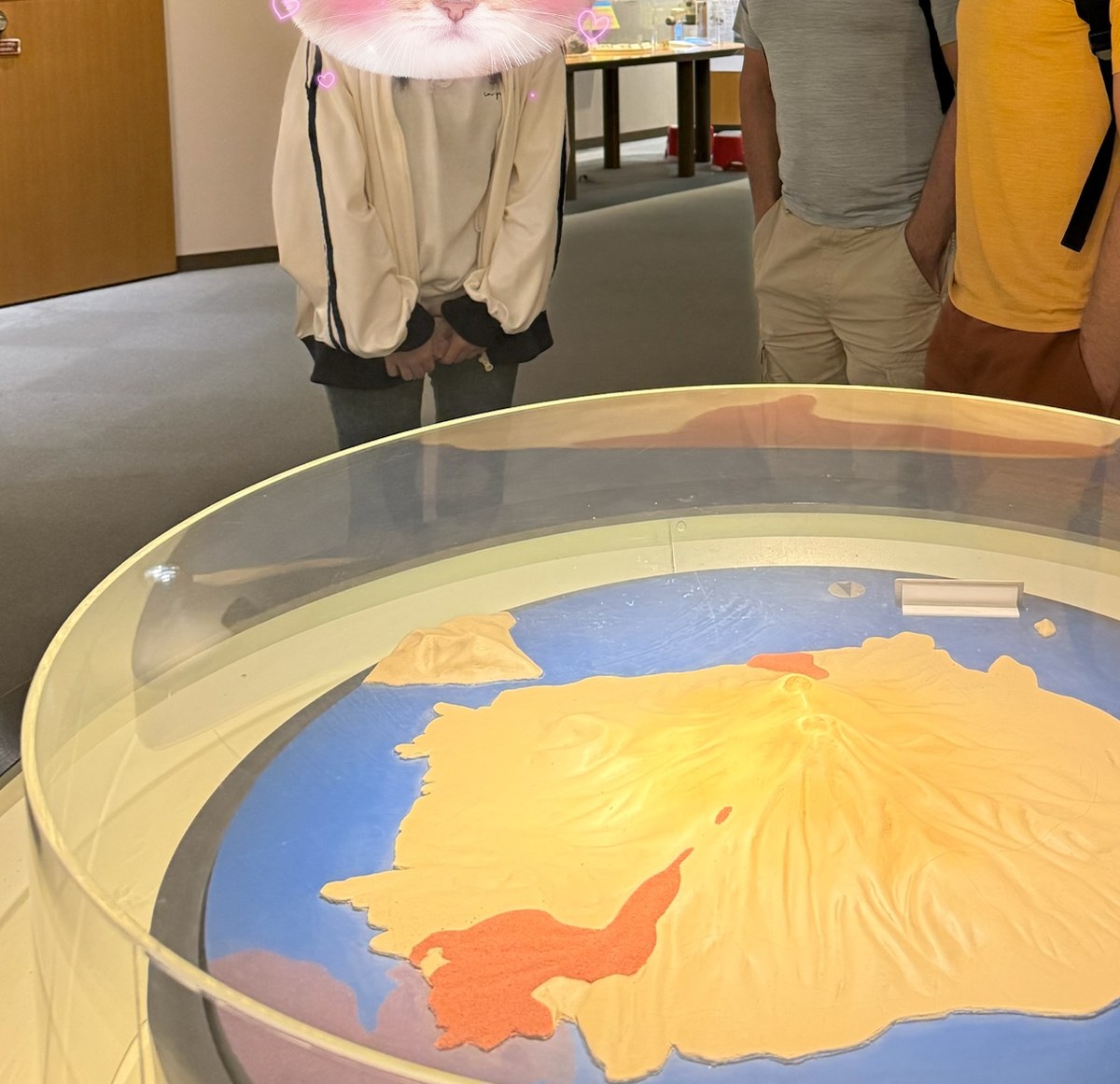 A student volunteer standing with international guests at a visitor centre in Kagoshima