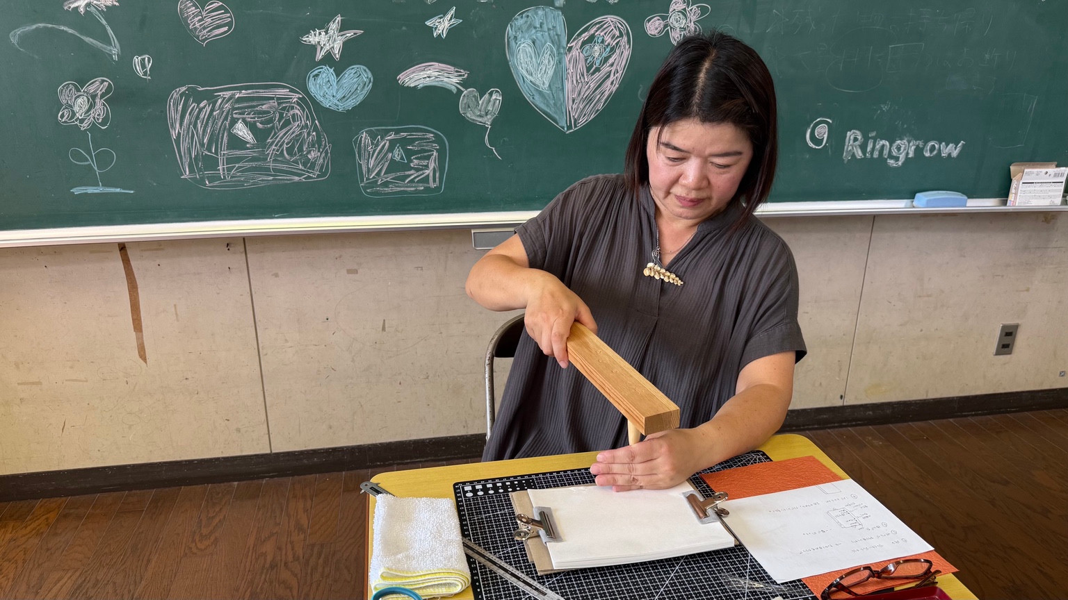 A workshop participant working on her notebook at a table in a former classroom