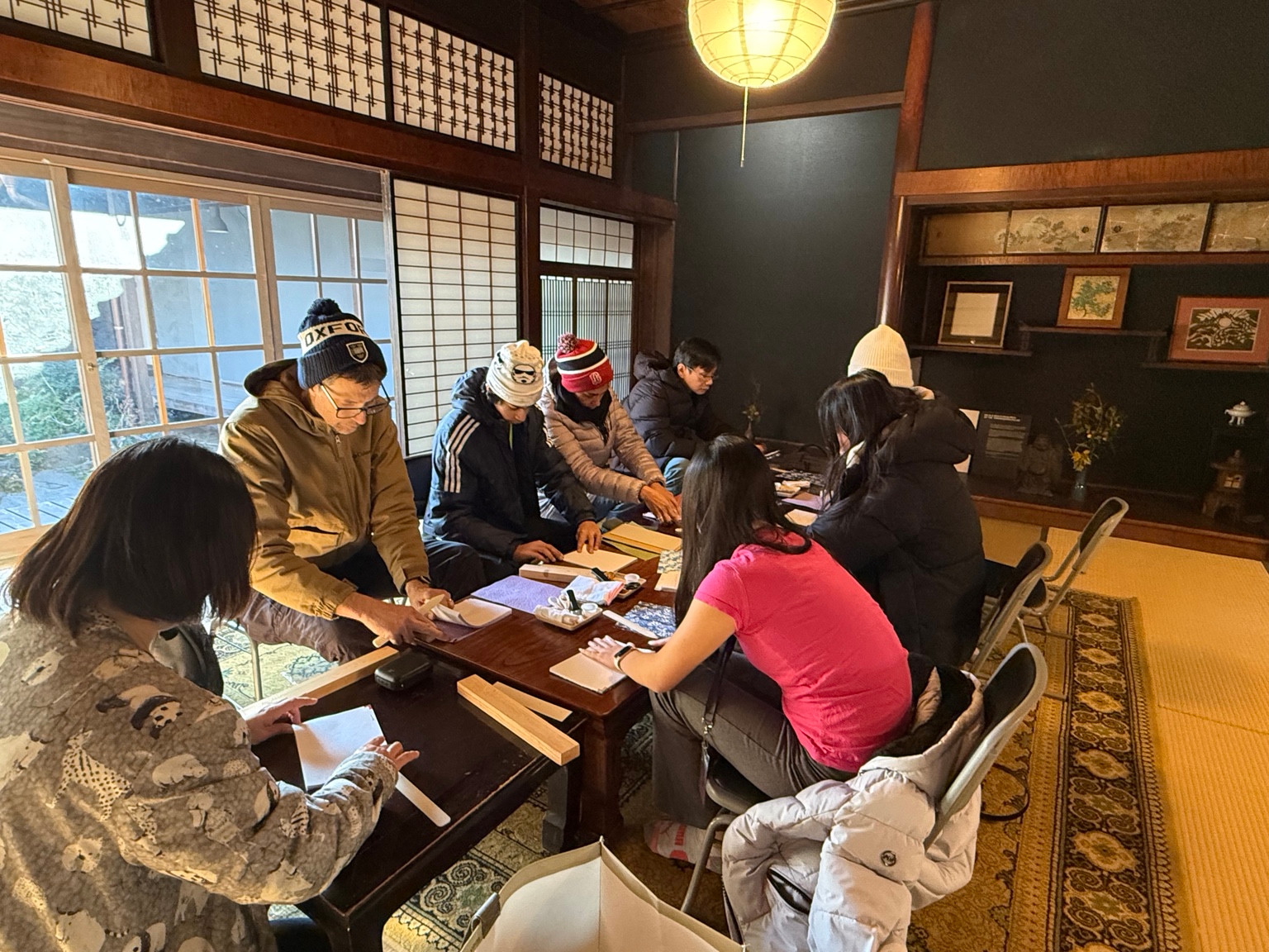 Participants making washi notebooks together around a table in a traditional Japanese room